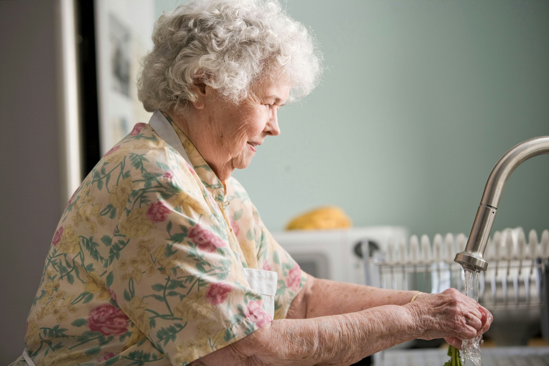 An older woman happily preparing food in her kitchen